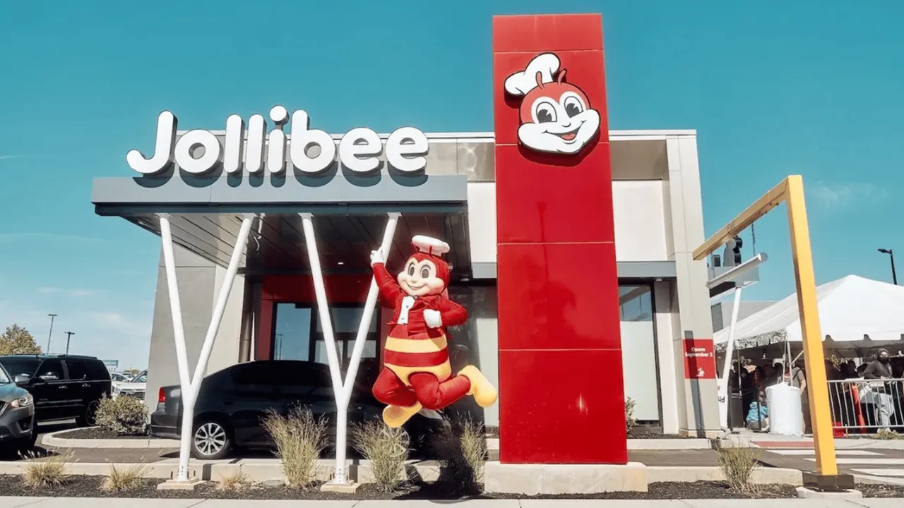 Image of jollibee mascot jumping in front of new franchise location