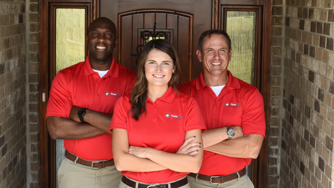 Photo of three HomeTeam team members standing in front of a home, smiling with arms crossed