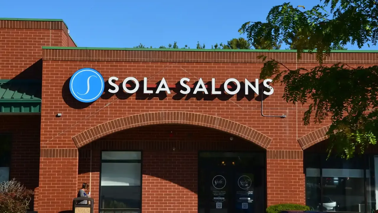 Photo of exterior of Sola Salons location with brick front and blue sign