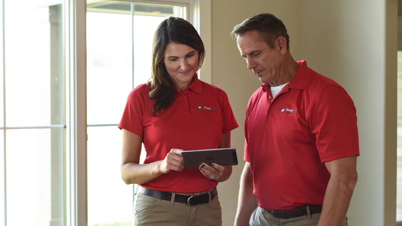 Photo of two HomeTeam inspectors standing together, looking at tablet