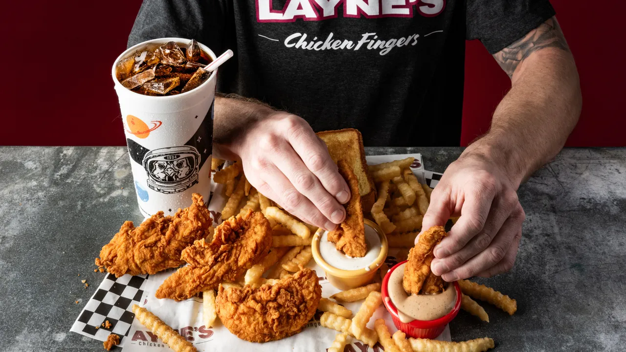 Photo of person dipping Layne's Chicken Fingers into signature sauces