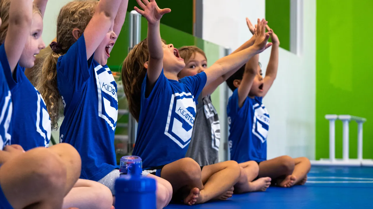 Photo of multiple young children wearing KidStrong shirts, participating in KidStrong activities