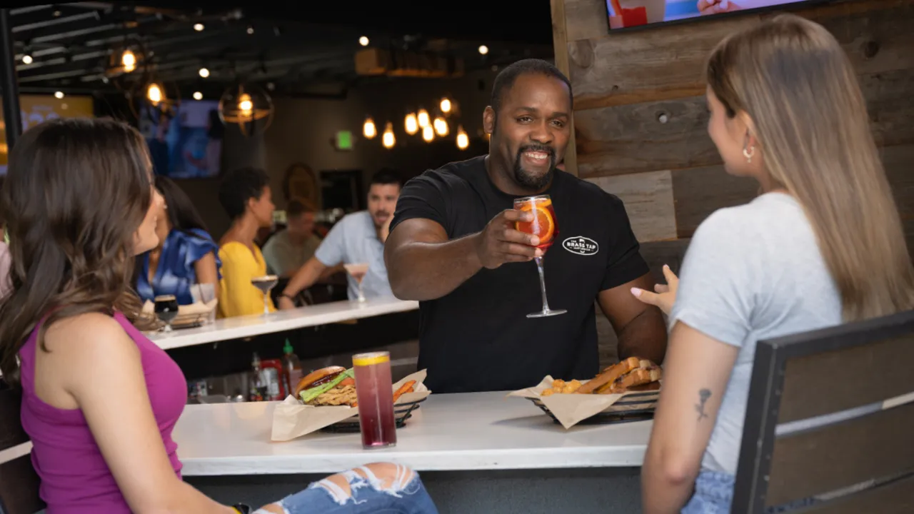 Photo of Brass Tap team member serving two guests