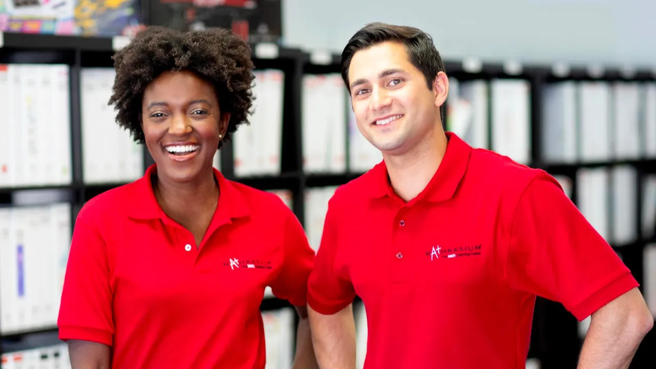 Photo of two people wearing Mathnasium branded shirts, smiling at camera