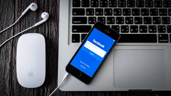 Facebook app on a phone that's resting on a computer.