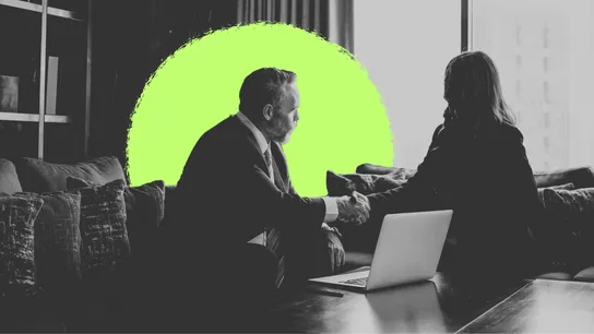 black & white image of two business people shaking hands with a laptop on the table in front of them