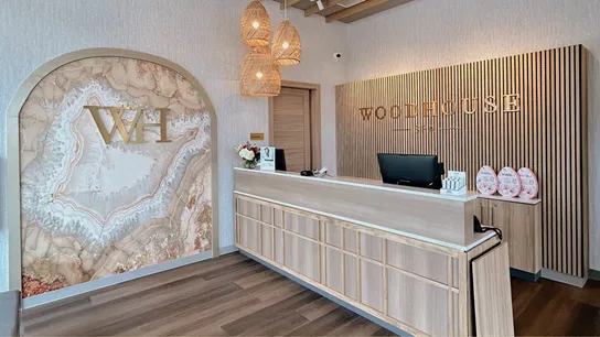 Photo of front desk of Woodhouse Spa featuring pendant lights, wood flooring, and marbled art