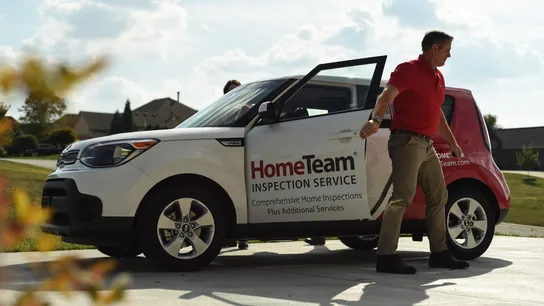 Photo of HomeTeam team member exiting branded vehicle in khakis and red polo