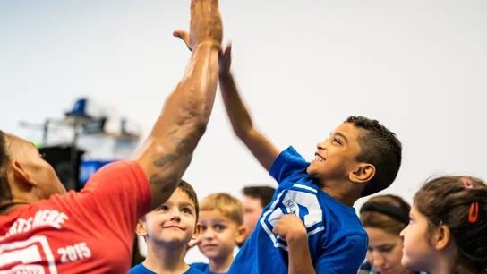 Image of a kid growing up, developing with kidstrong, high fiving and smiling. 