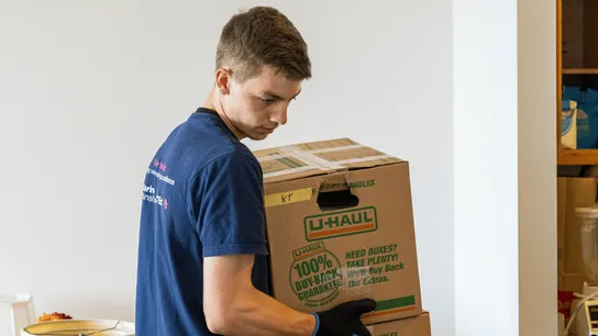 image of a man carrying boxes for a disabled person for caring transitions in a small town