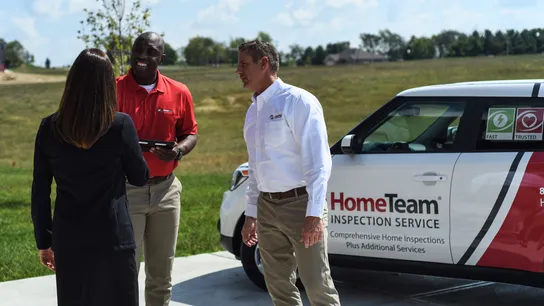 Photo of home inspectors speaking with another person outside of HomeTeam Inspection Service vehicle