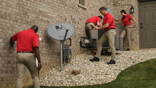 Photo of four HomeTeam Inspection Service team members inspecting exterior of home