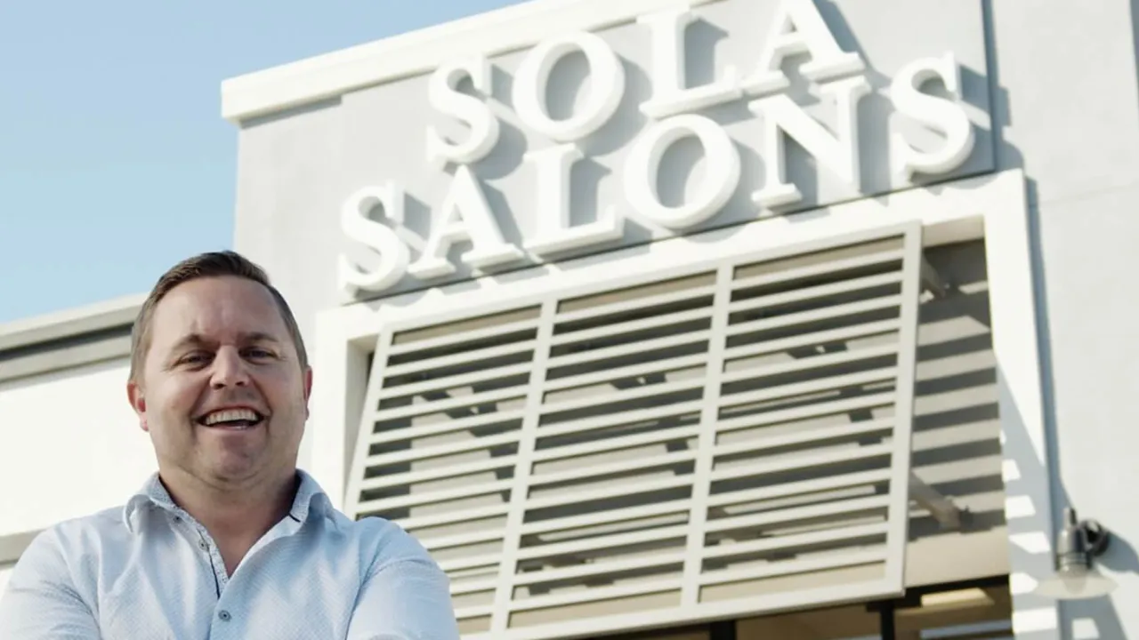 sola salons franchise owner stands, smiling, in front of the business