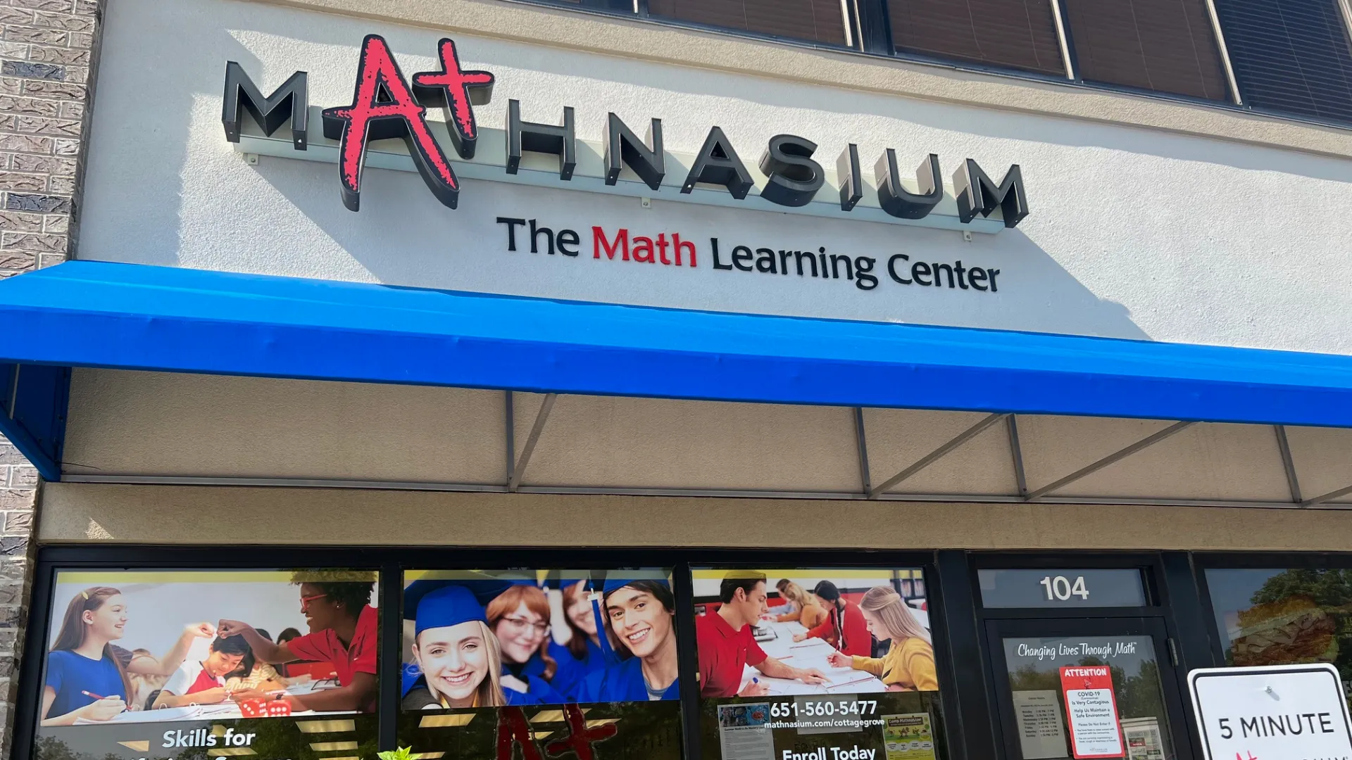 exterior of a Mathnasium building with a blue awning and photos of students in windows