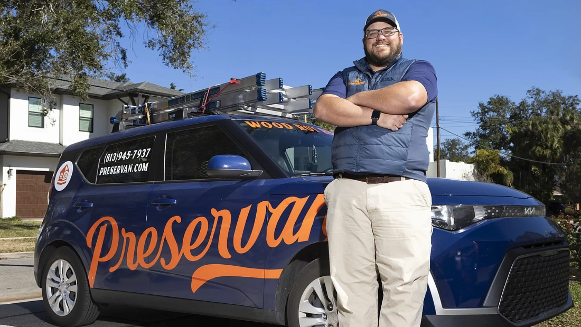 photo of JW Ferguson, wearing khakis and a blue shirt, standing in front of his Preservan vehicle