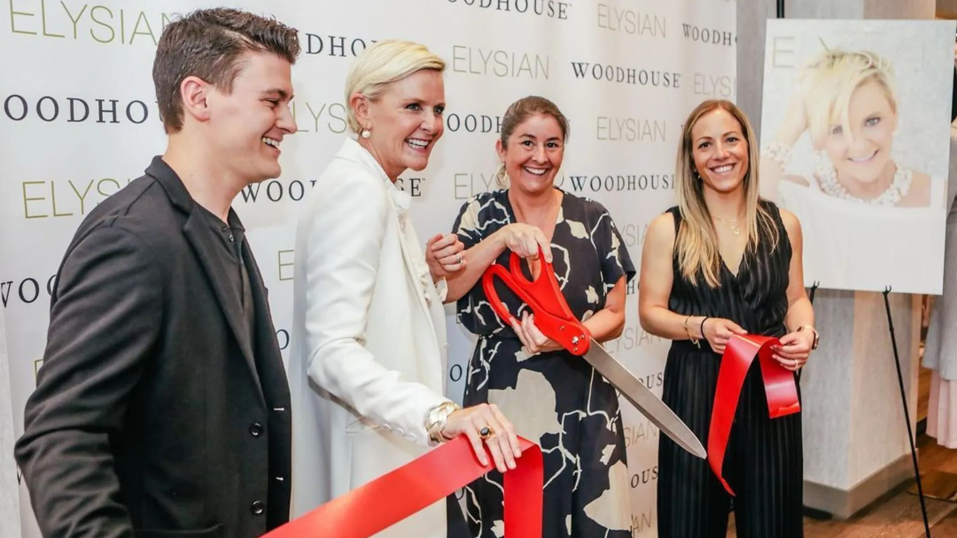 four people stand, smiling, at the ribbon cutting for Woodhouse Spa Elysian