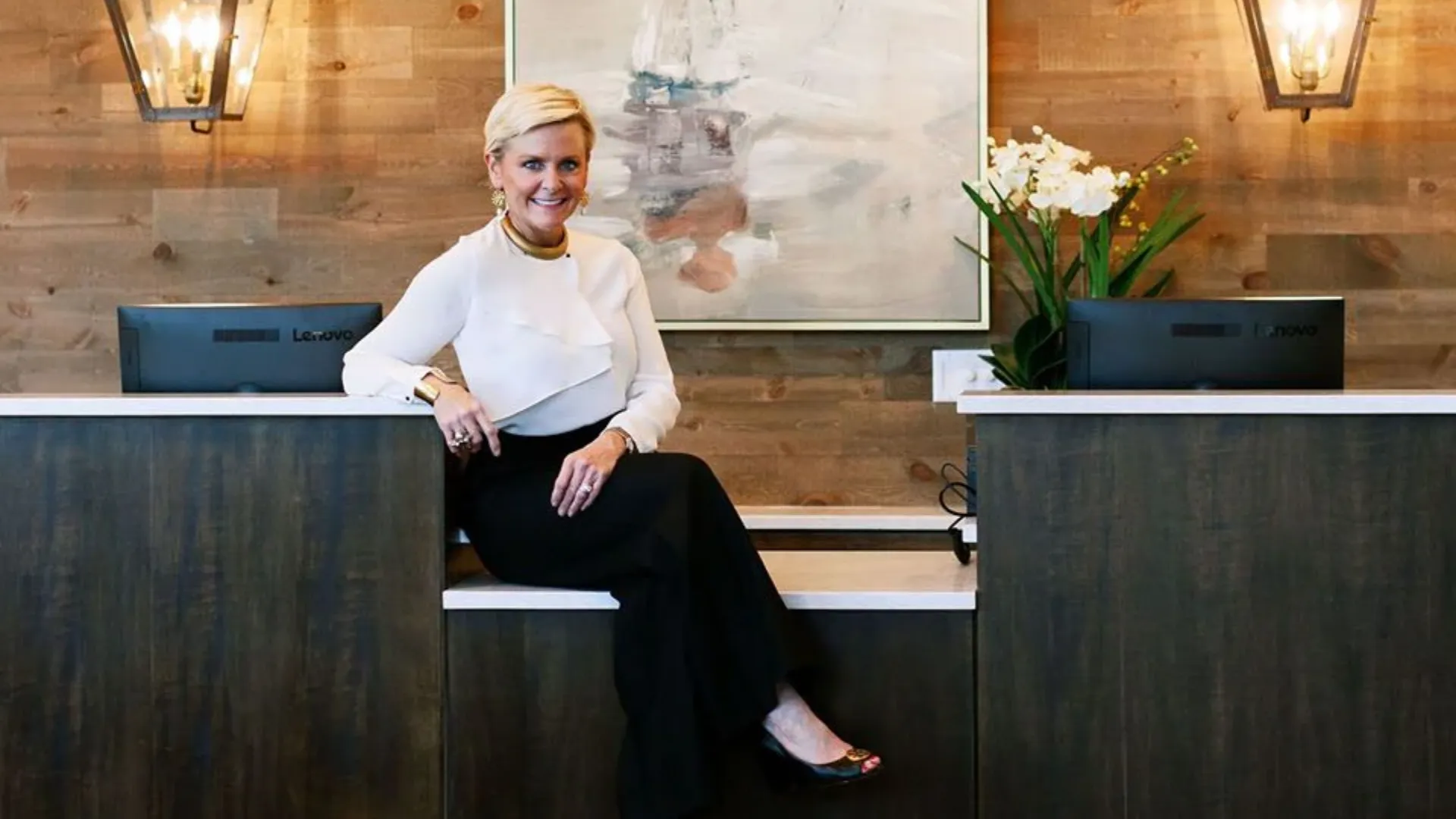 photo of Woodhouse Spas franchisee sitting on front desk wearing a white top and black bottoms