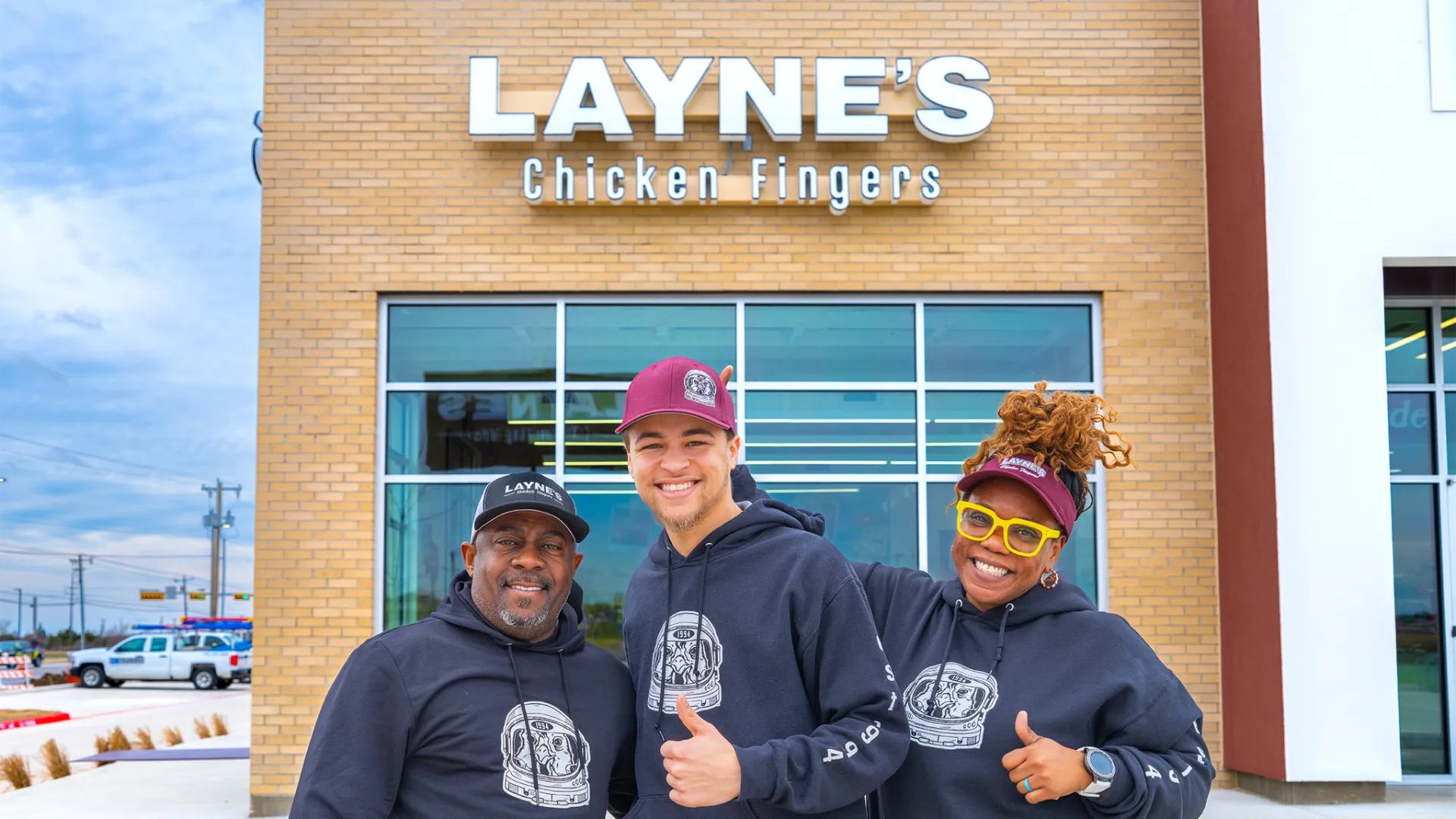 photo of three Layne's Chicken Fingers team members, standing outside a new location, smiling