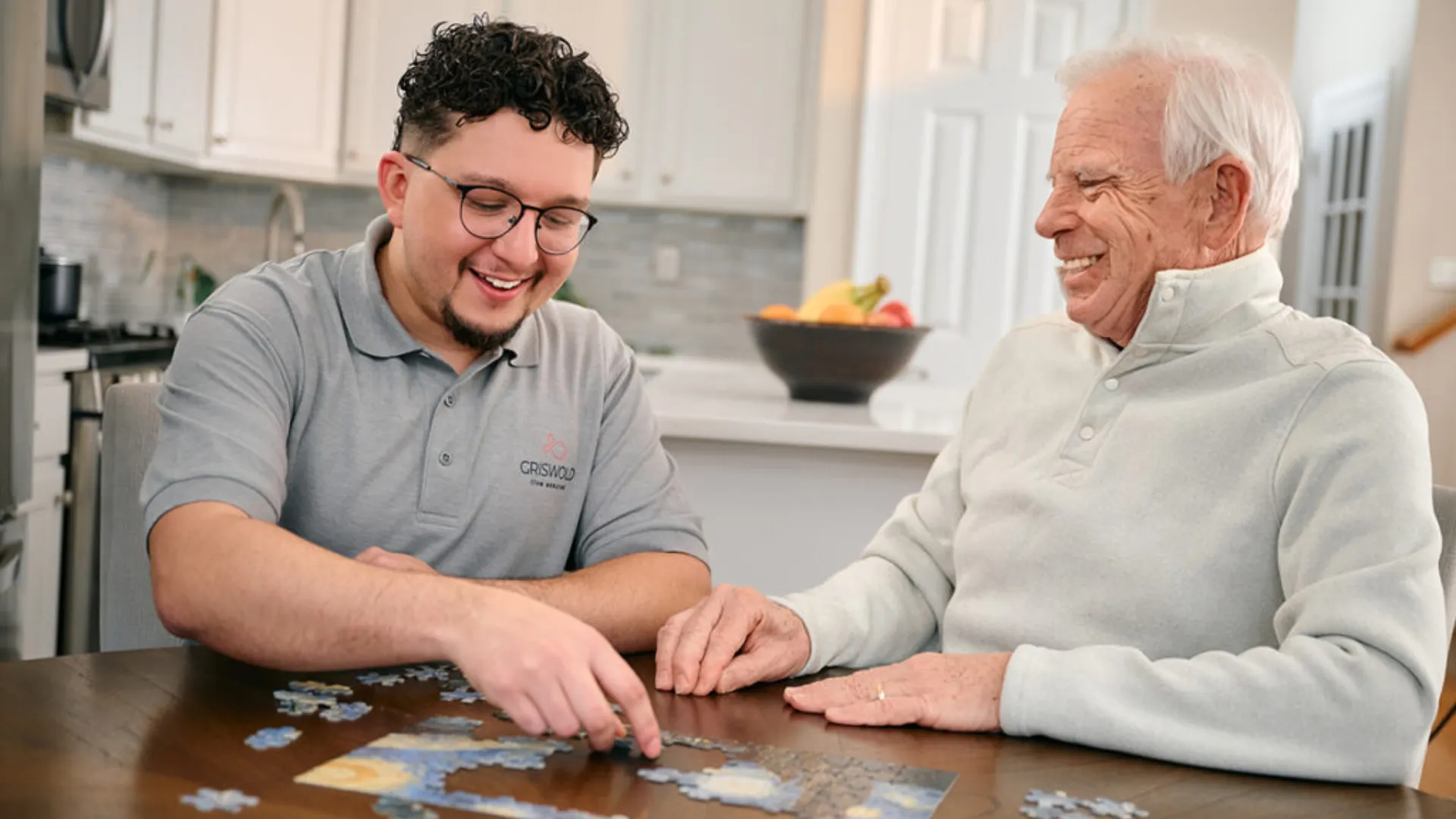 photo of Griswold team member sitting at a kitchen table, completing a puzzle with client