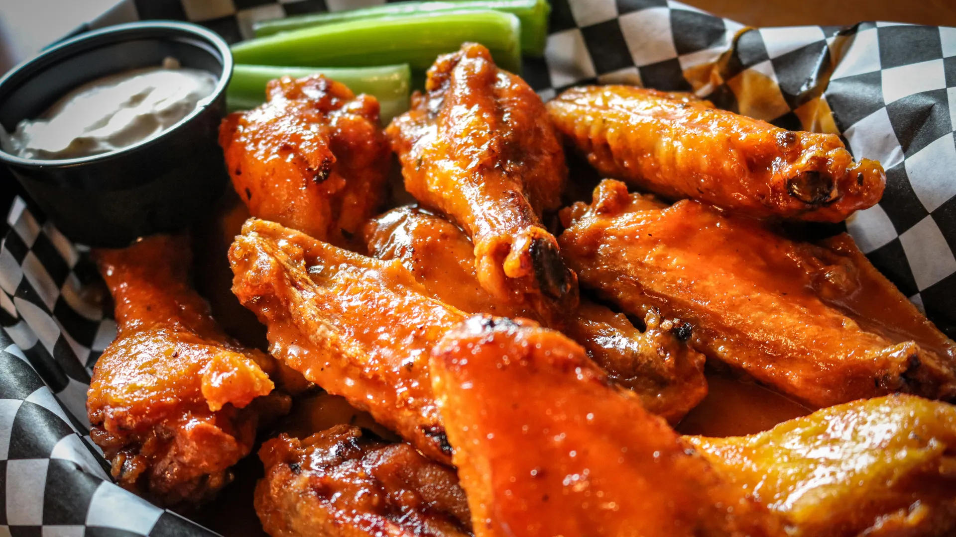 Photo of a basket of chicken wings with dipping sauce and celery