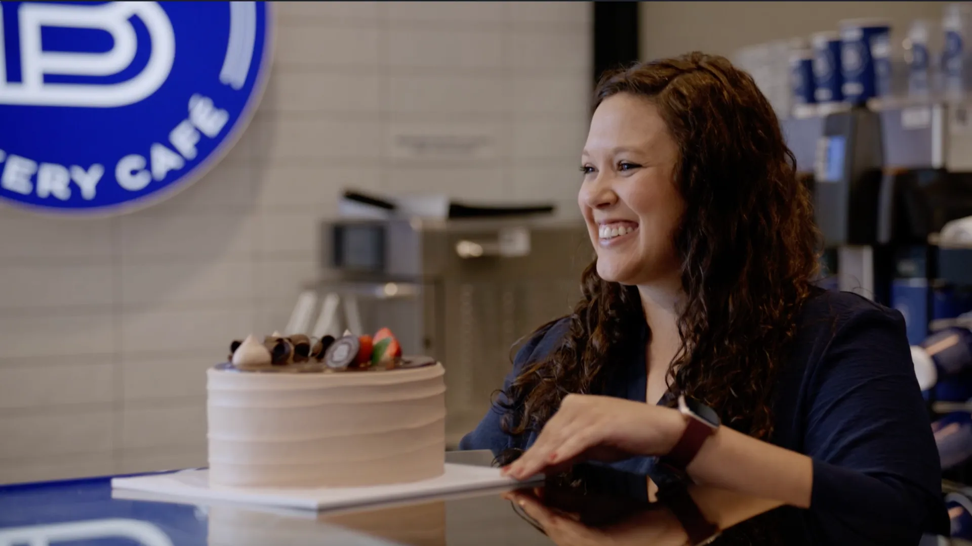 photo of Paris Baguette professional smiling, presenting chocolate cake with strawberries on top