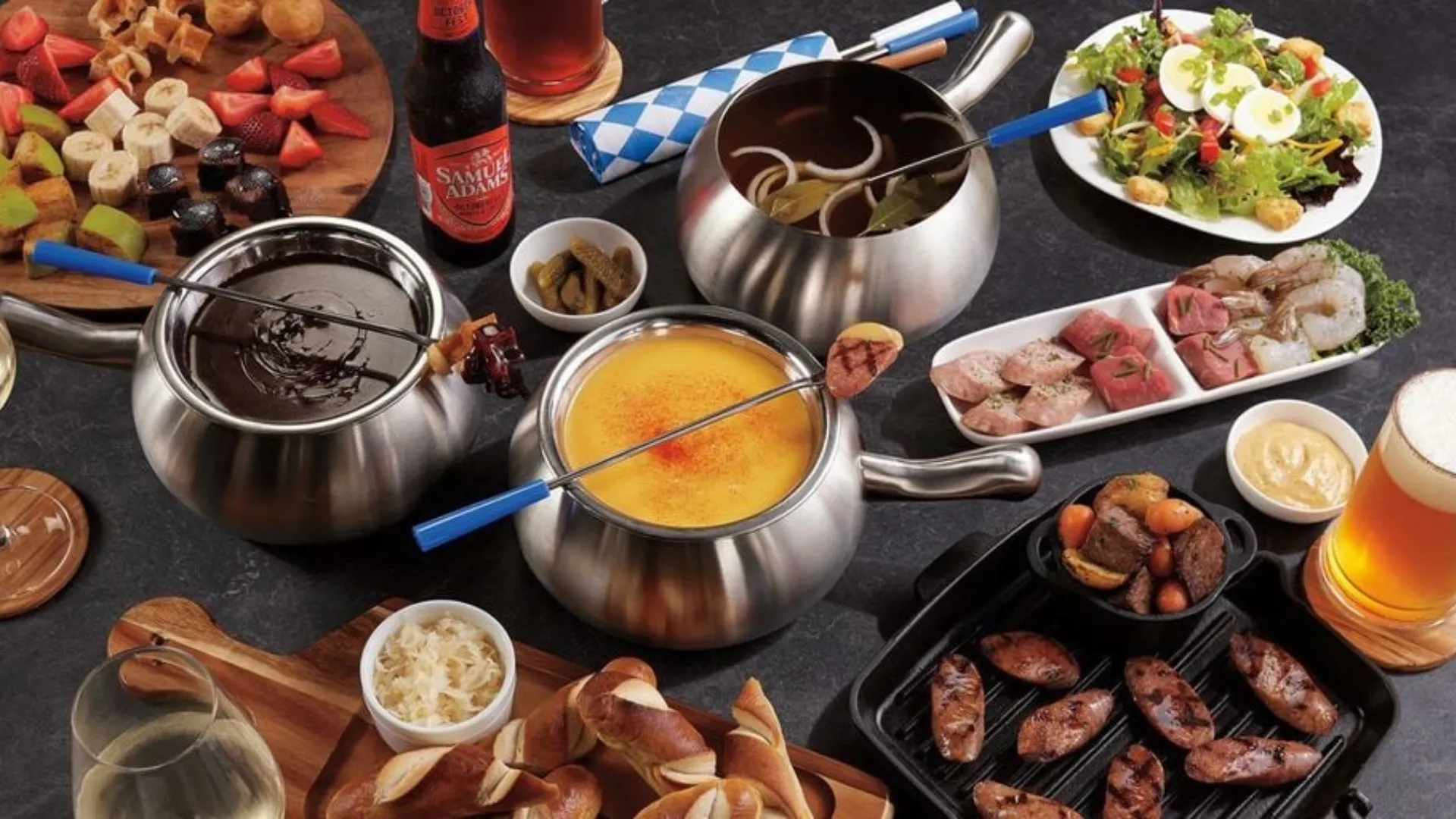 Photo of Melting Pot fondue spread with cheese and chocolate, bread, meats and fruits