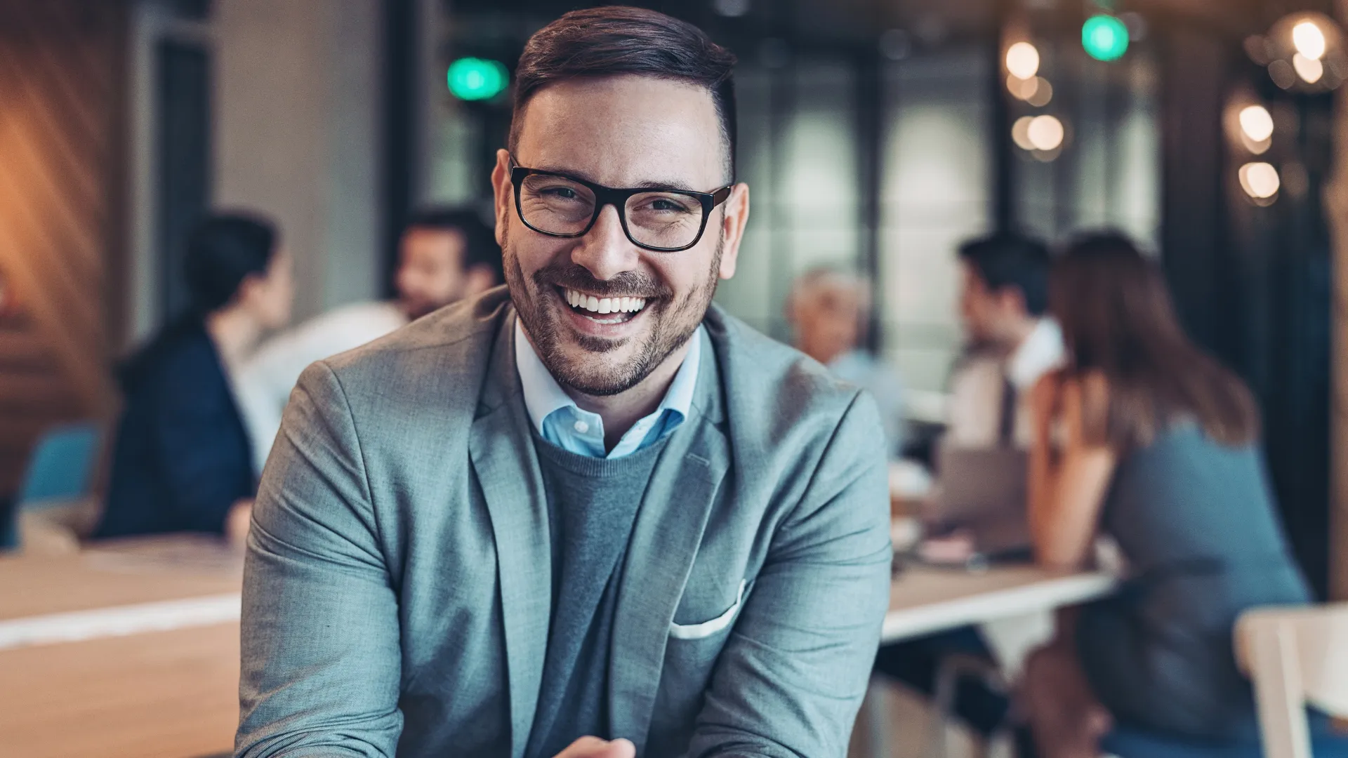 Photo of a businessman, wearing glasses, smiling at the camera