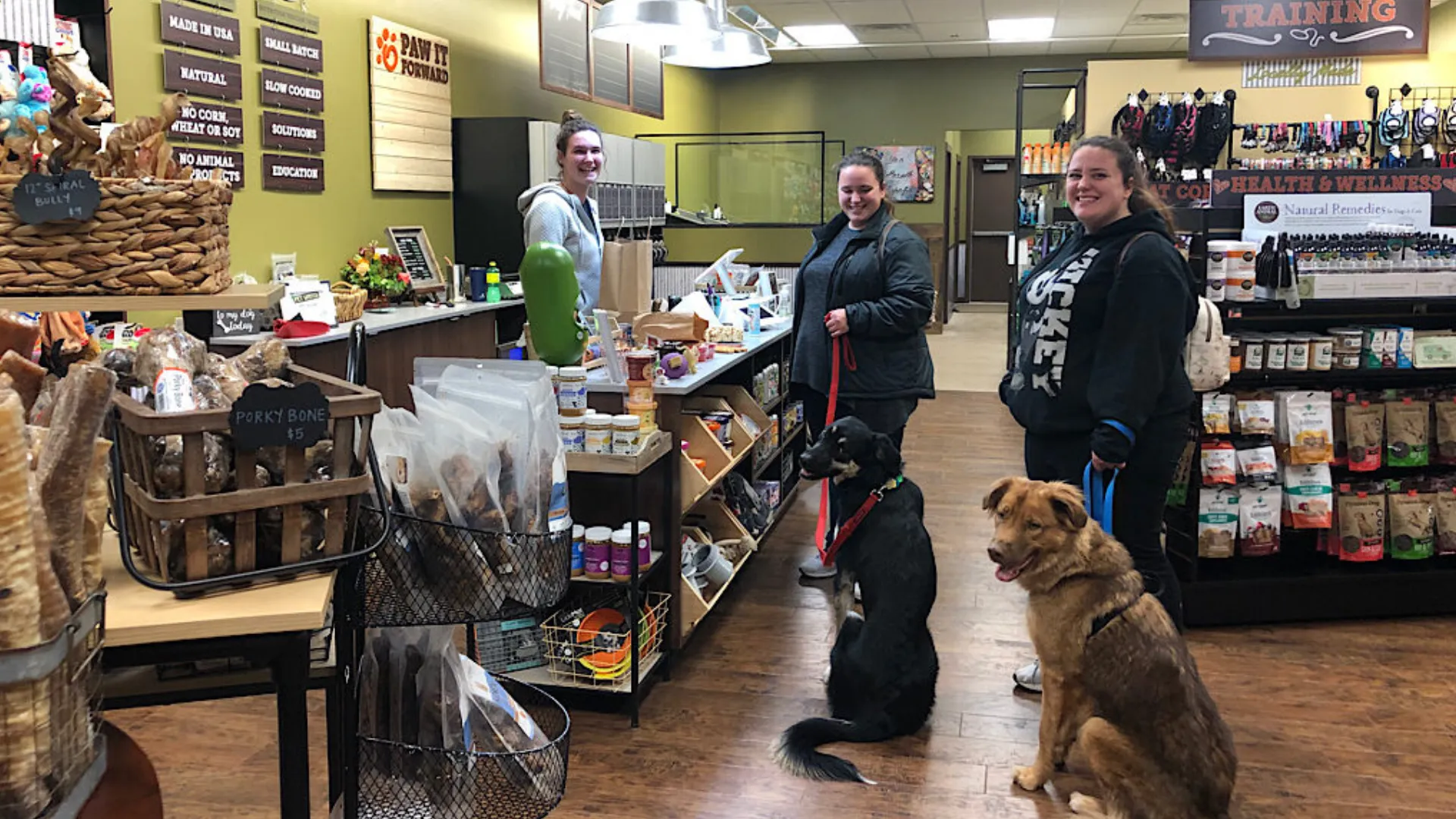 Photo of two customers, with two dogs, and an employee in a Pet Wants location