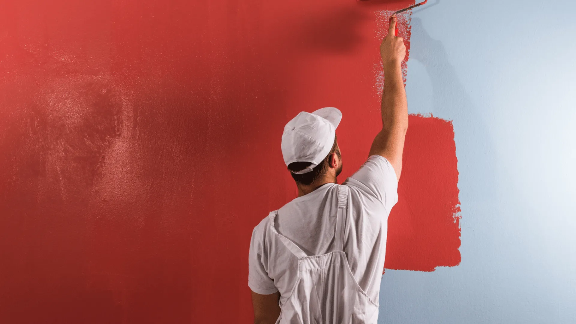 photo of Fresh Coat team member wearing white work clothes, painting a wall red