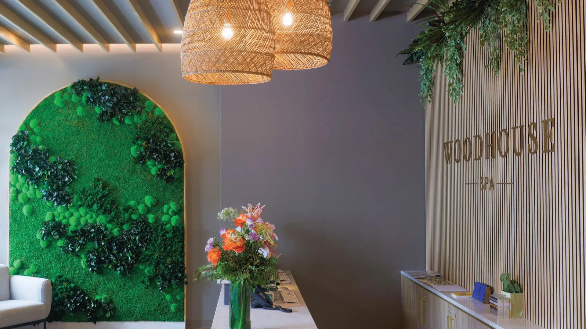 photo of Woodhouse Spa front desk with flowers, greenery, and pendant lights