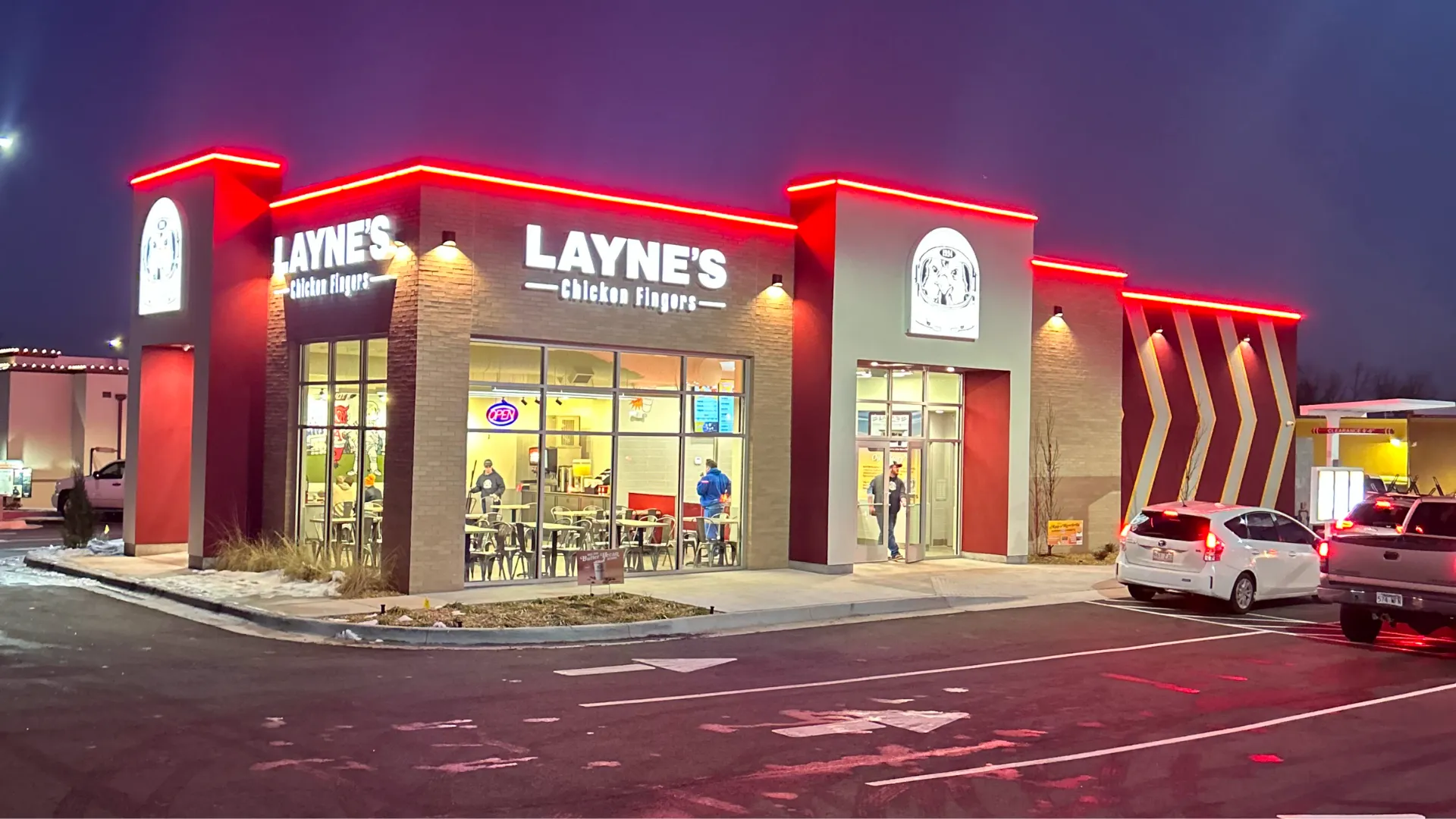 Photo of Layne's Chicken Fingers restaurant after dark with red lights around top of building