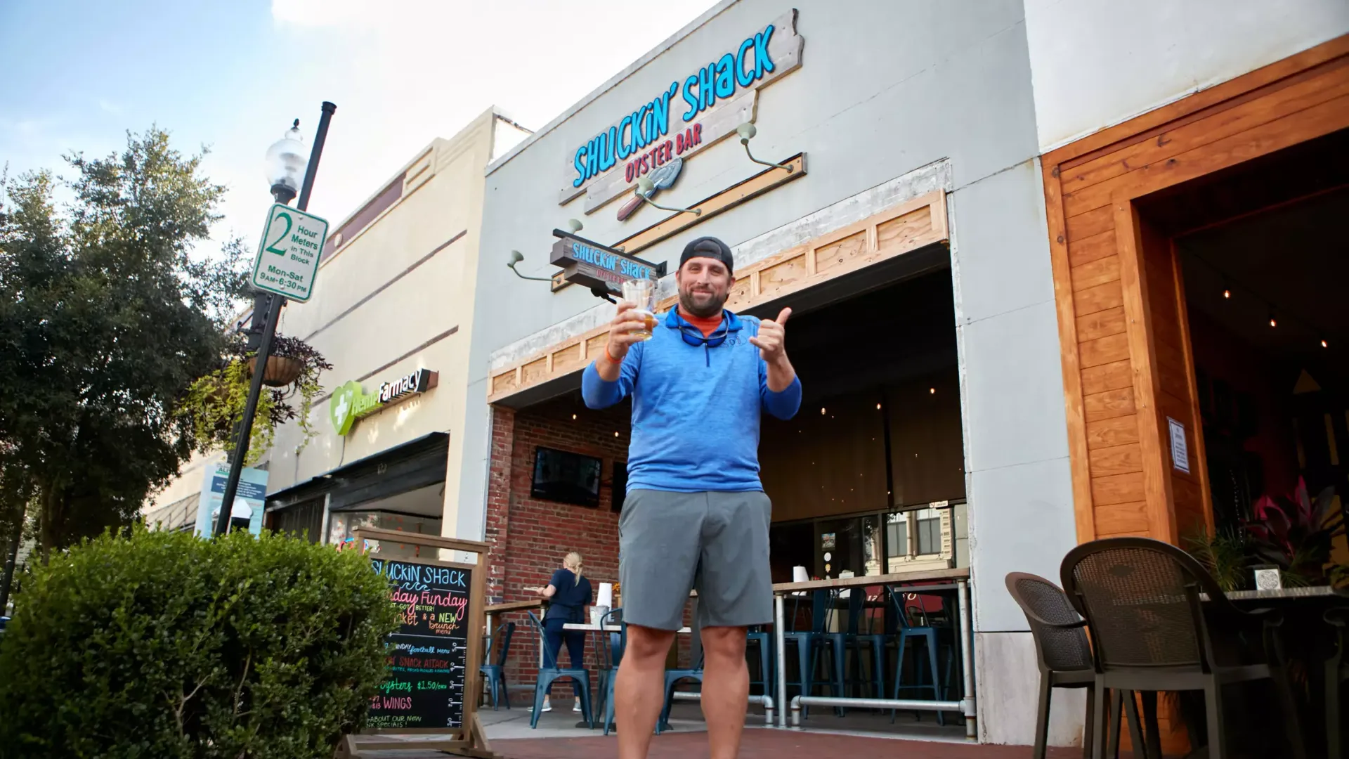 Photo of person in blue shirt and gray shorts standing outside Shuckin' Shack Oyster Bar