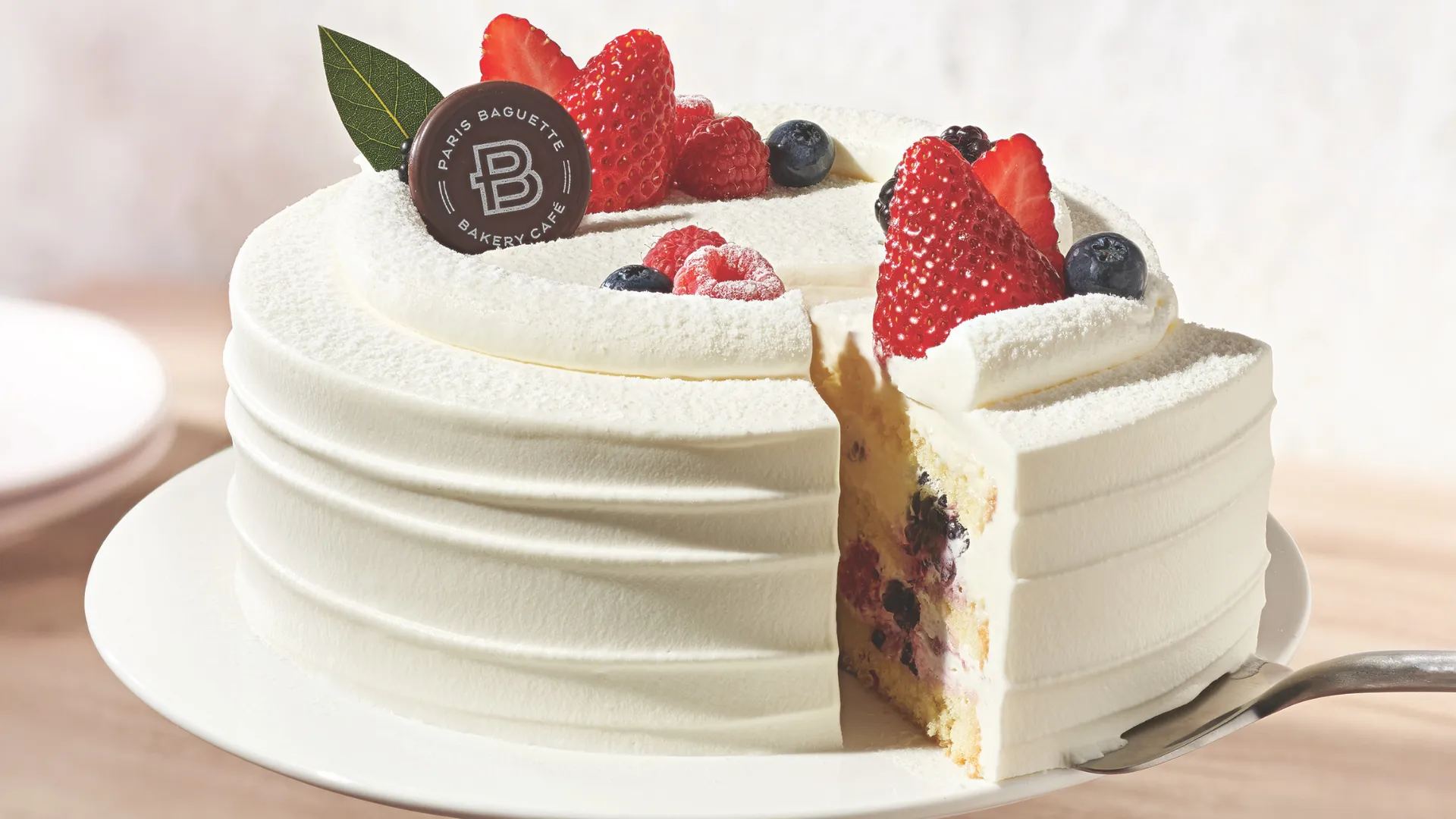 Photo of Paris Baguette cake featuring layers with cream and berries, topped with fresh berries