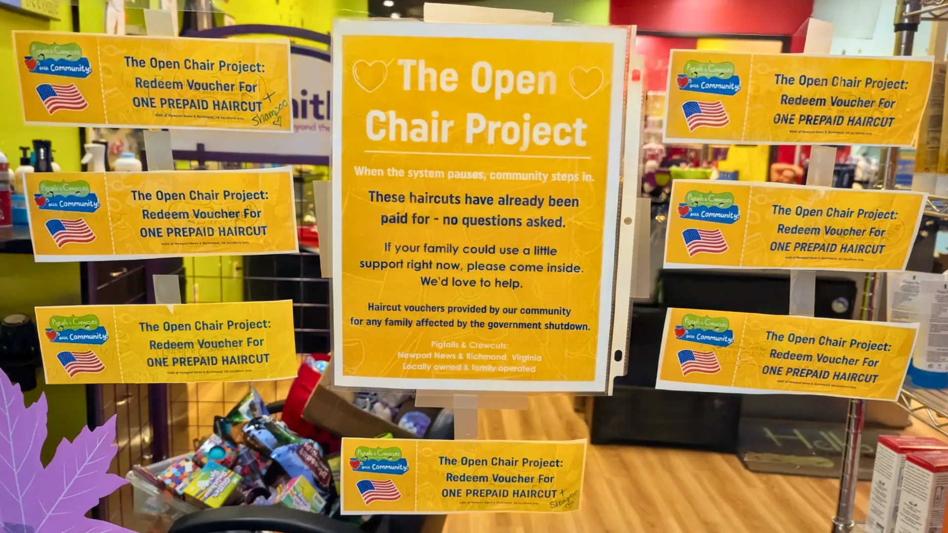 Photo of Pigtails & Crewcuts window with Open Chair Project vouchers hanging up