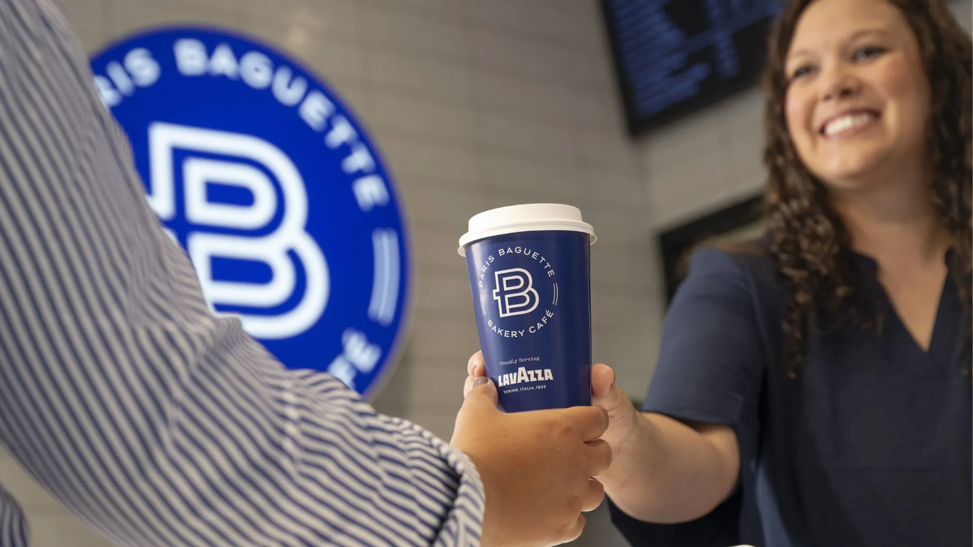 Photo of person handing blue Paris Baguette coffee cup to guest