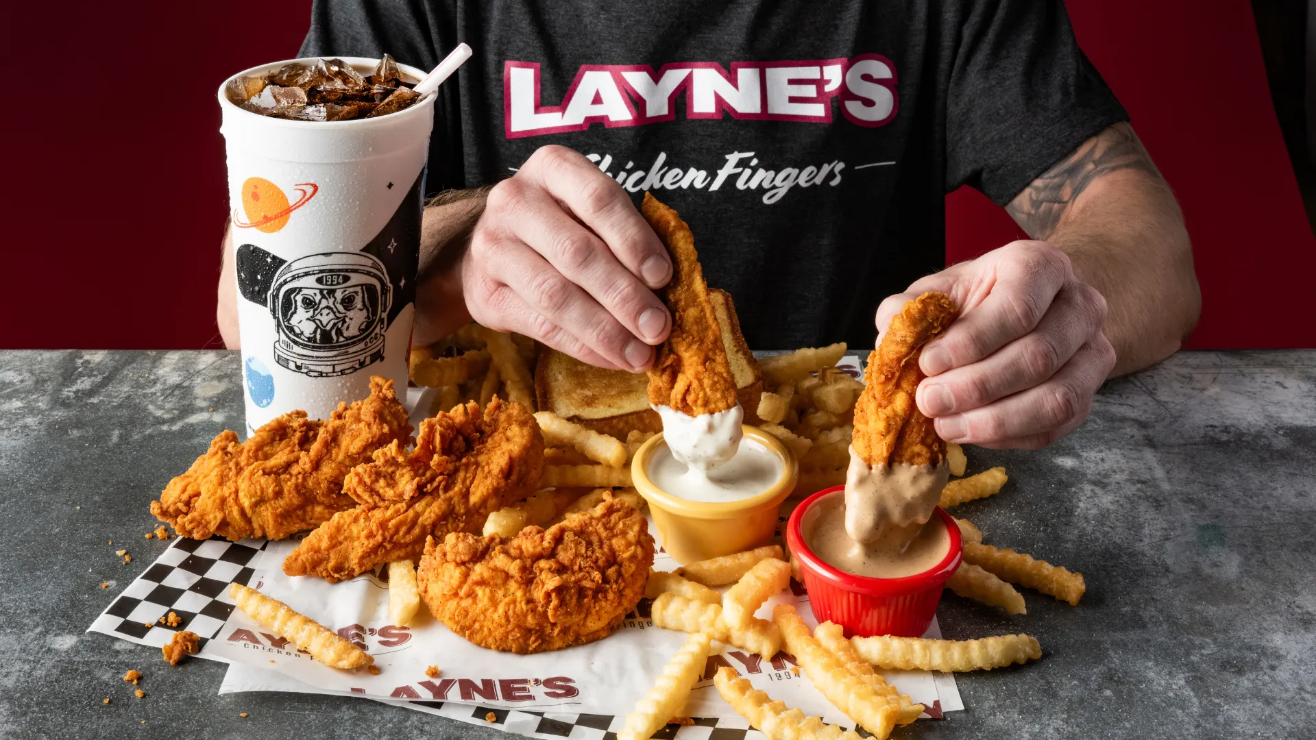 Photo of person dipping Layne's Chicken Fingers in sauce