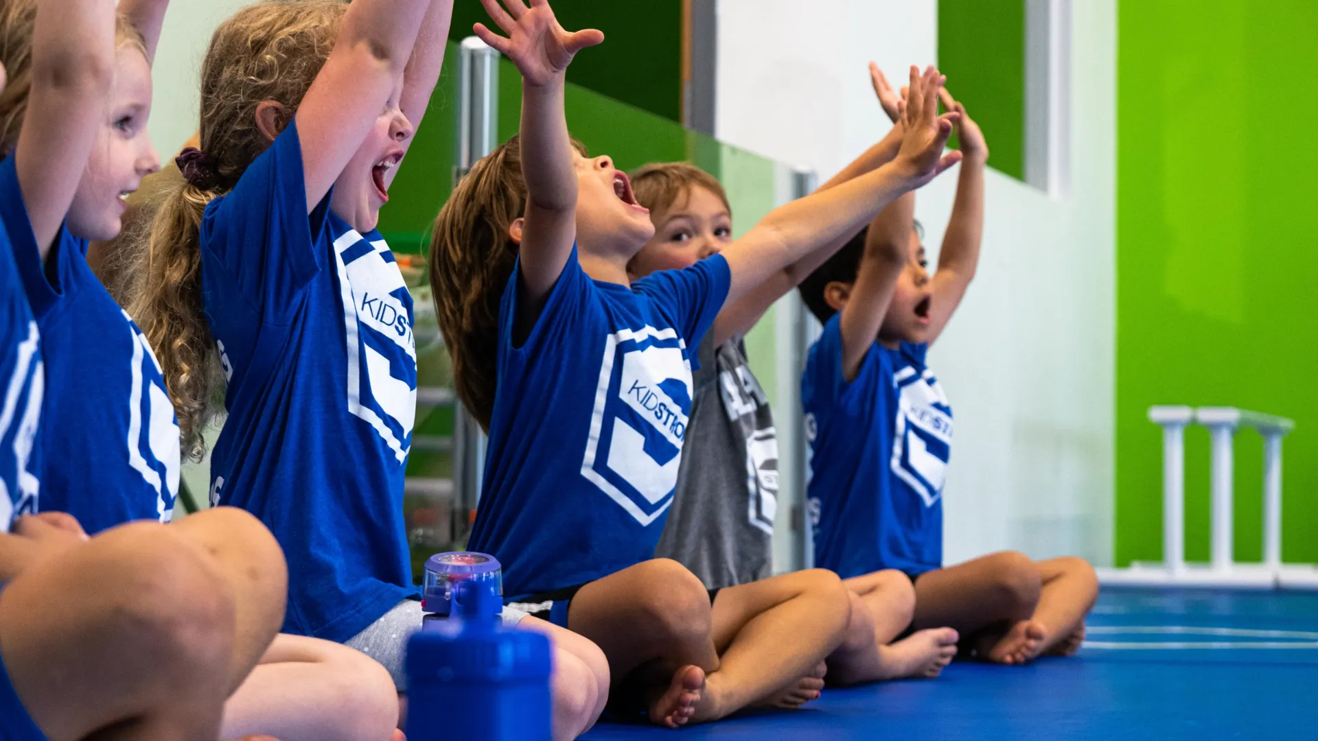 Photo of multiple young children wearing KidStrong shirts, participating in KidStrong activities