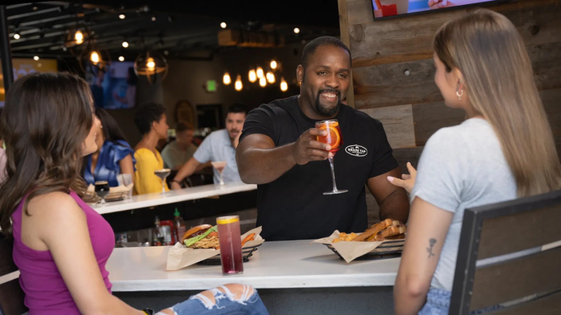 Photo of Brass Tap team member serving two guests