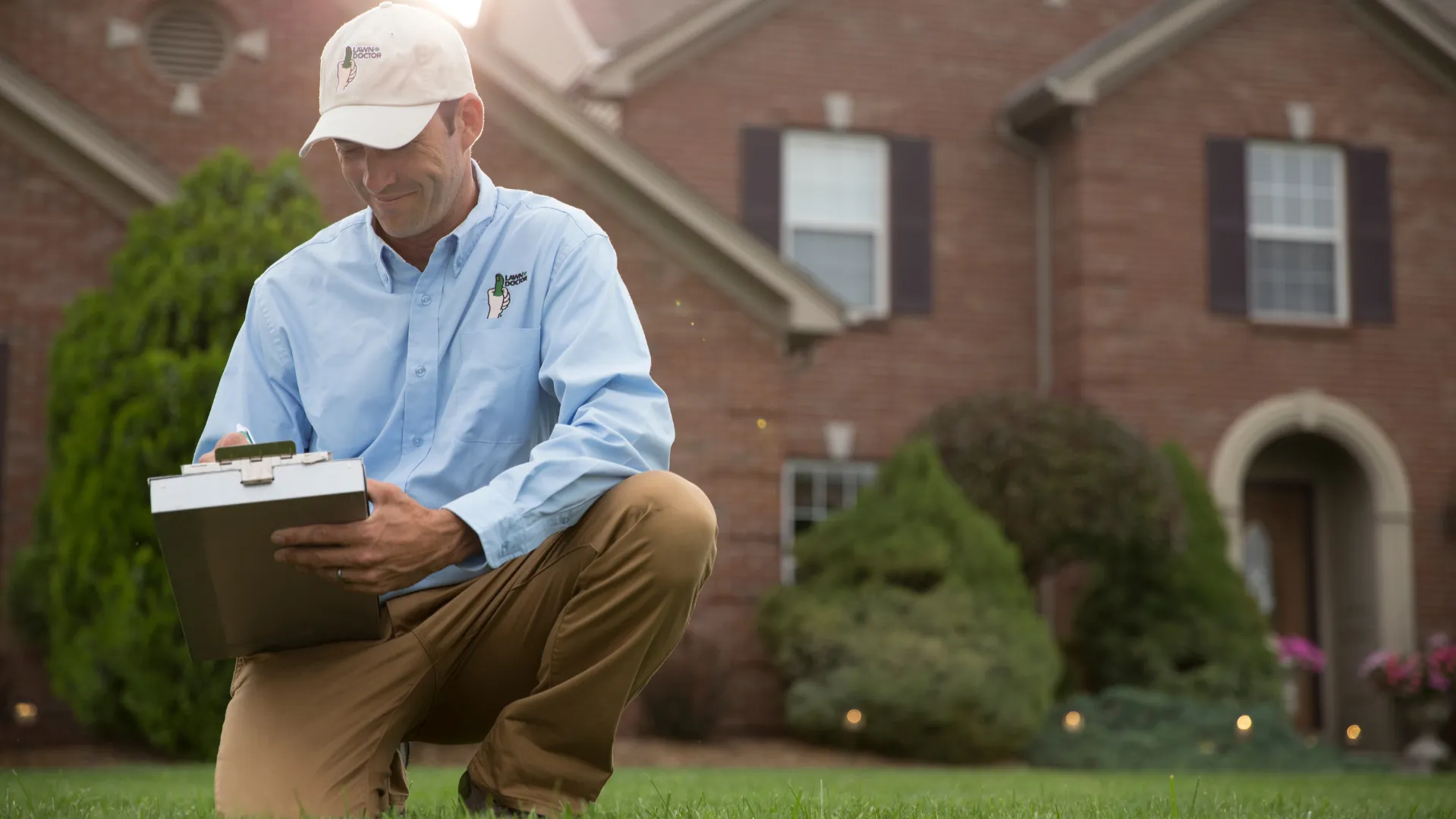 Photo of Lawn Doctor team member working outside, wearing blue button-down and khakis